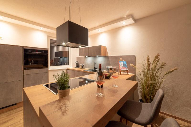 Die Küche am Abend, Weingläser auf der Bartheke, Backofen und Spüle