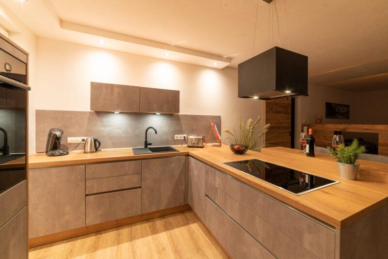 Die Küche abends, Kochfeld und Dunstabzugshaube sind im Zentrum