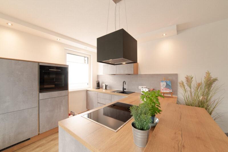 Die Küche bei Tageslicht mit Gartenkräutern vor dem Kochfeld