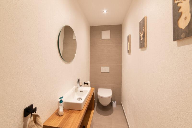 Die Gästetoilette mit Wandspiegel und Bildern