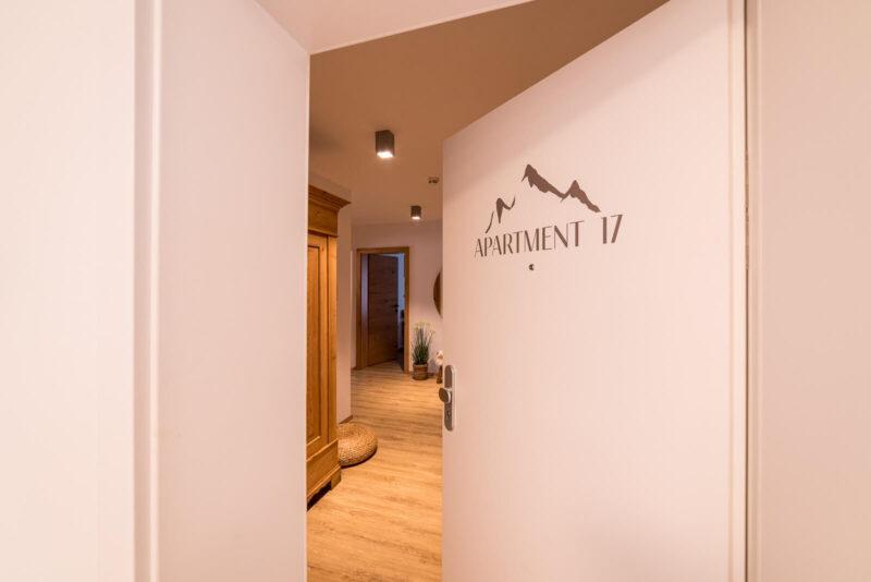 Man sieht die Eingangstür mit dem Logo, dahinter der Flur